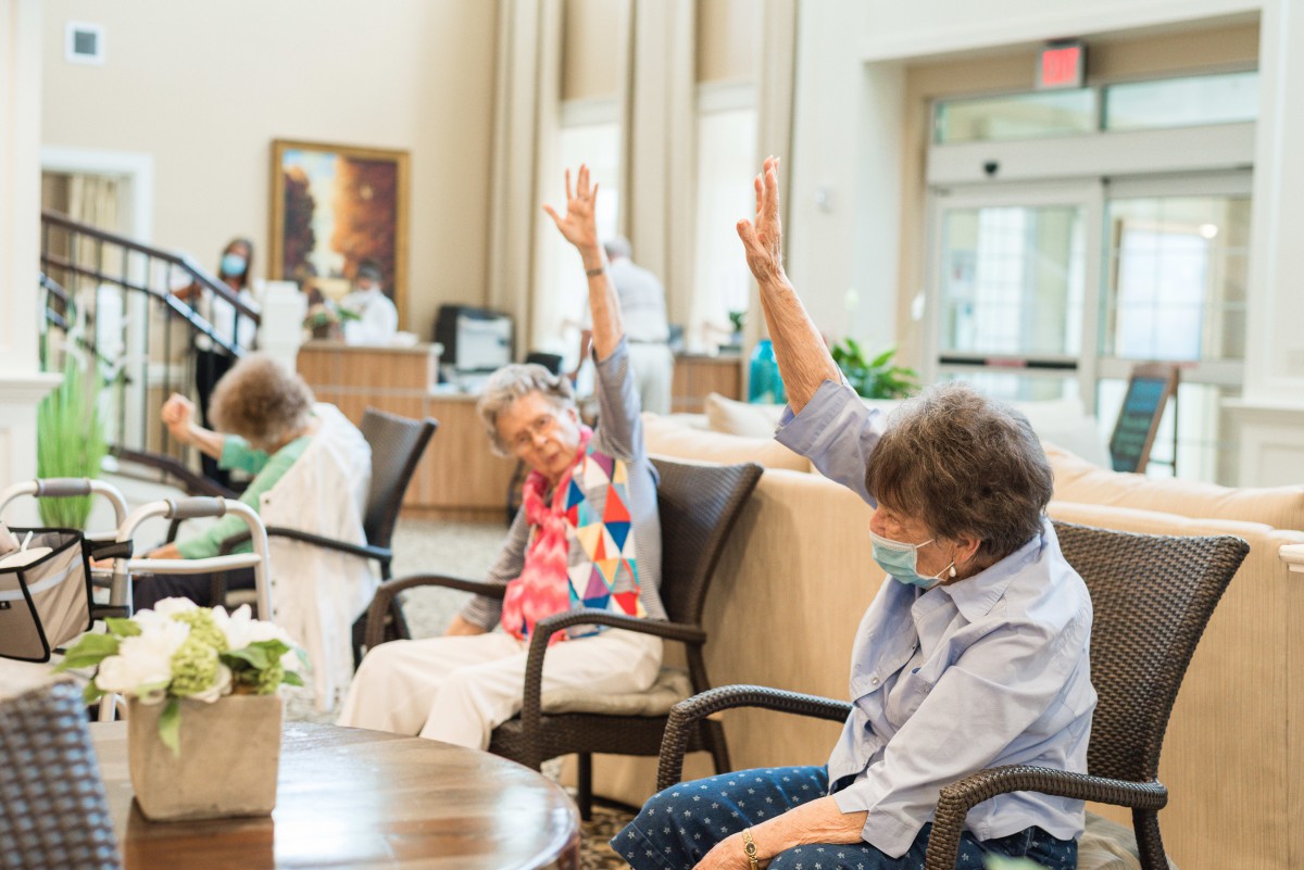 Seniors participating in a group chair exercise session indoors.