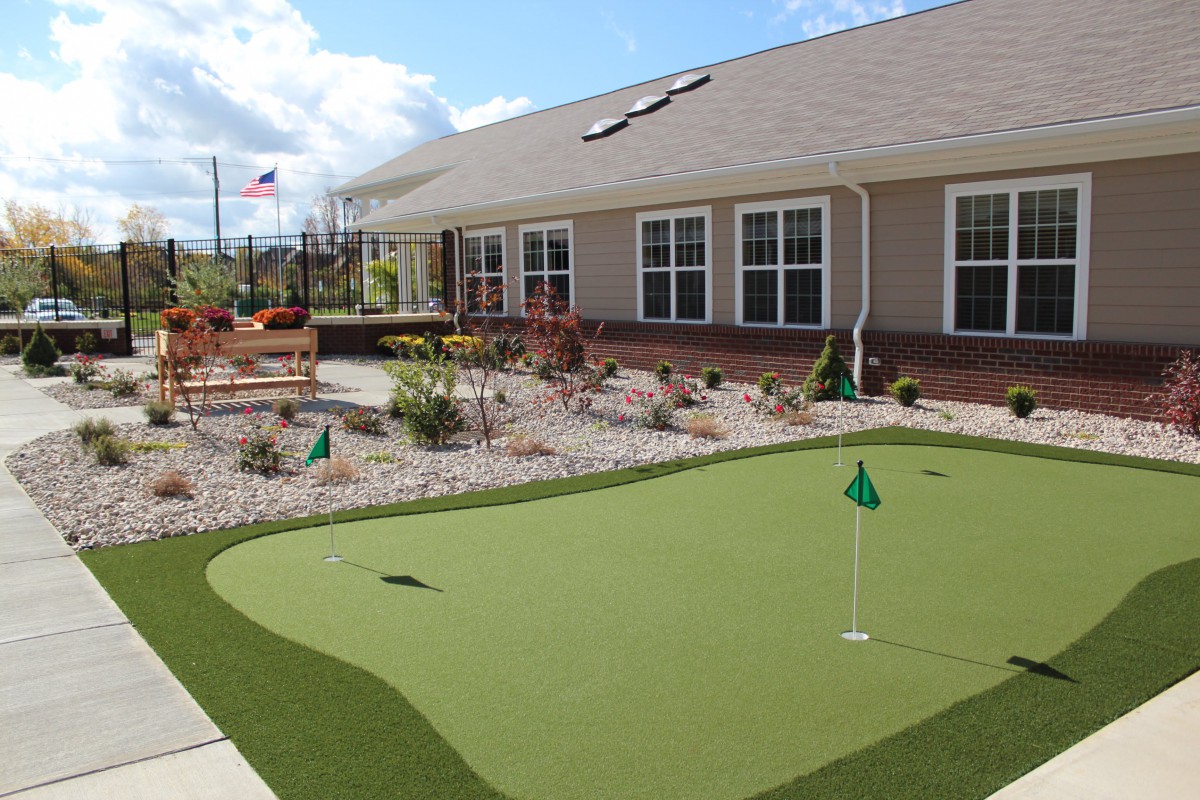 An outdoor putting green next to a building, providing a space for recreation and relaxation.