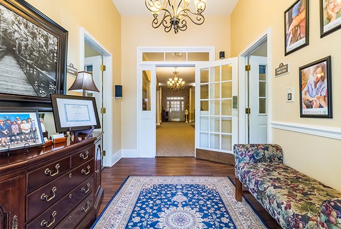 A welcoming foyer with elegant dcor, featuring a chandelier and a patterned rug.