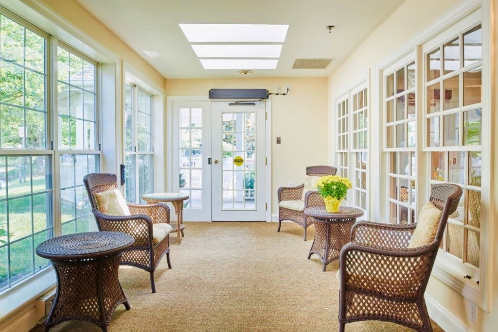 A cozy sunroom with wicker furniture and large windows, bathed in natural light.