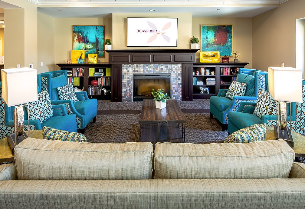 A cozy living room with a modern fireplace, comfortable seating, and colorful decor.
