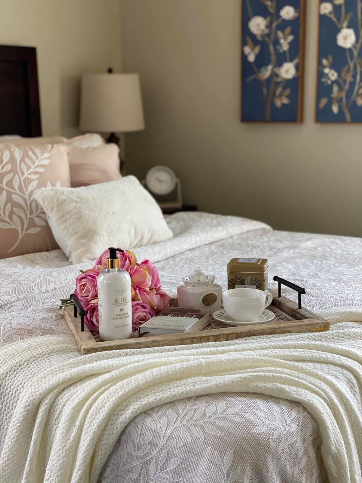 A cozy bedroom setup with a decorative tray featuring flowers and a cup, perfect for breakfast in bed.