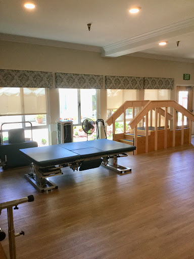 A spacious and well-lit physical therapy room equipped with exercise equipment and a wooden ramp for rehabilitation.