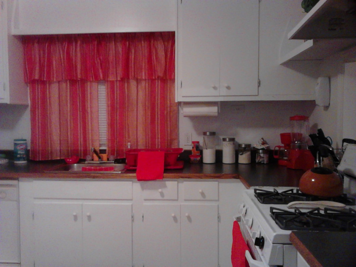 A cozy kitchen with red accents and white cabinetry.