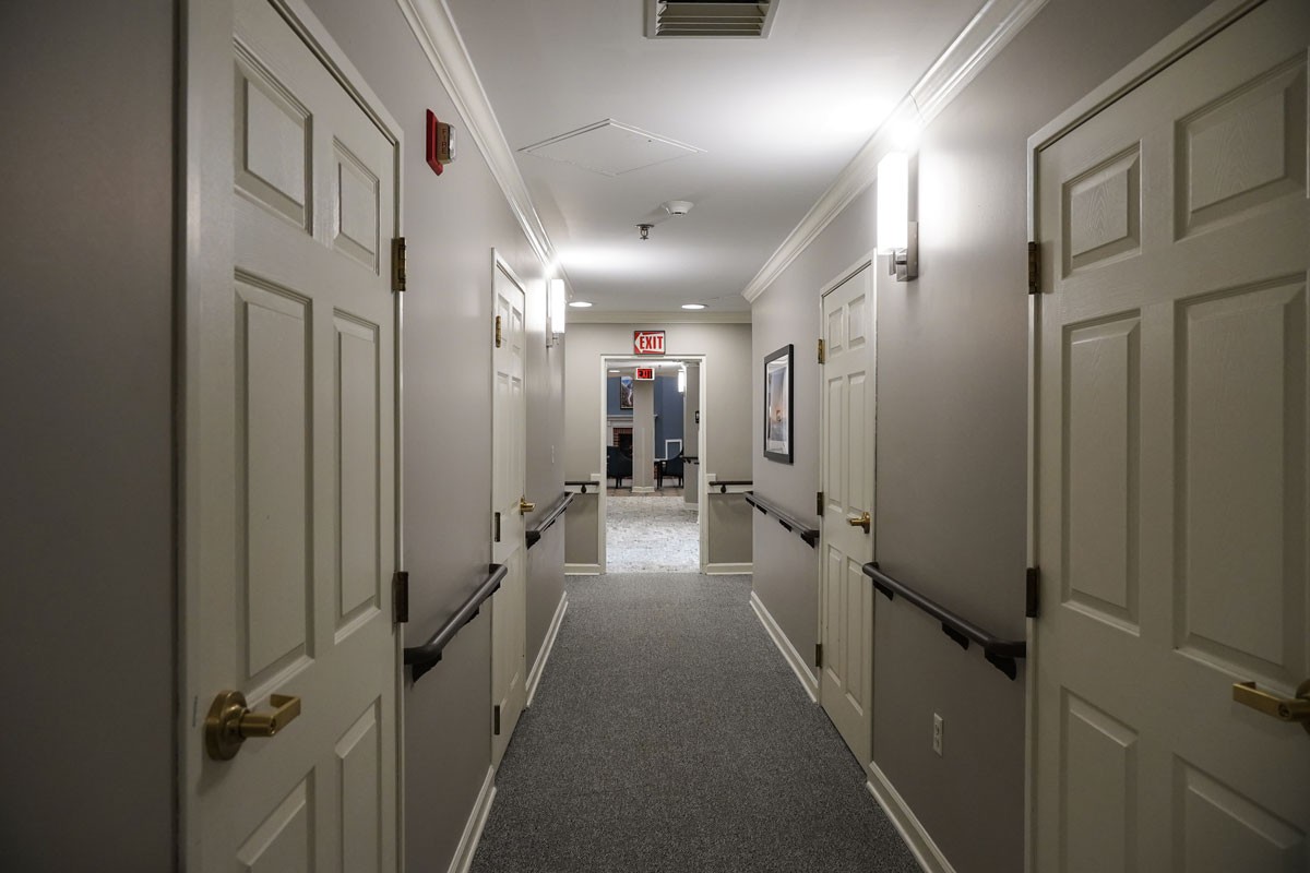 A well-lit hallway with multiple doors and a carpeted floor.
