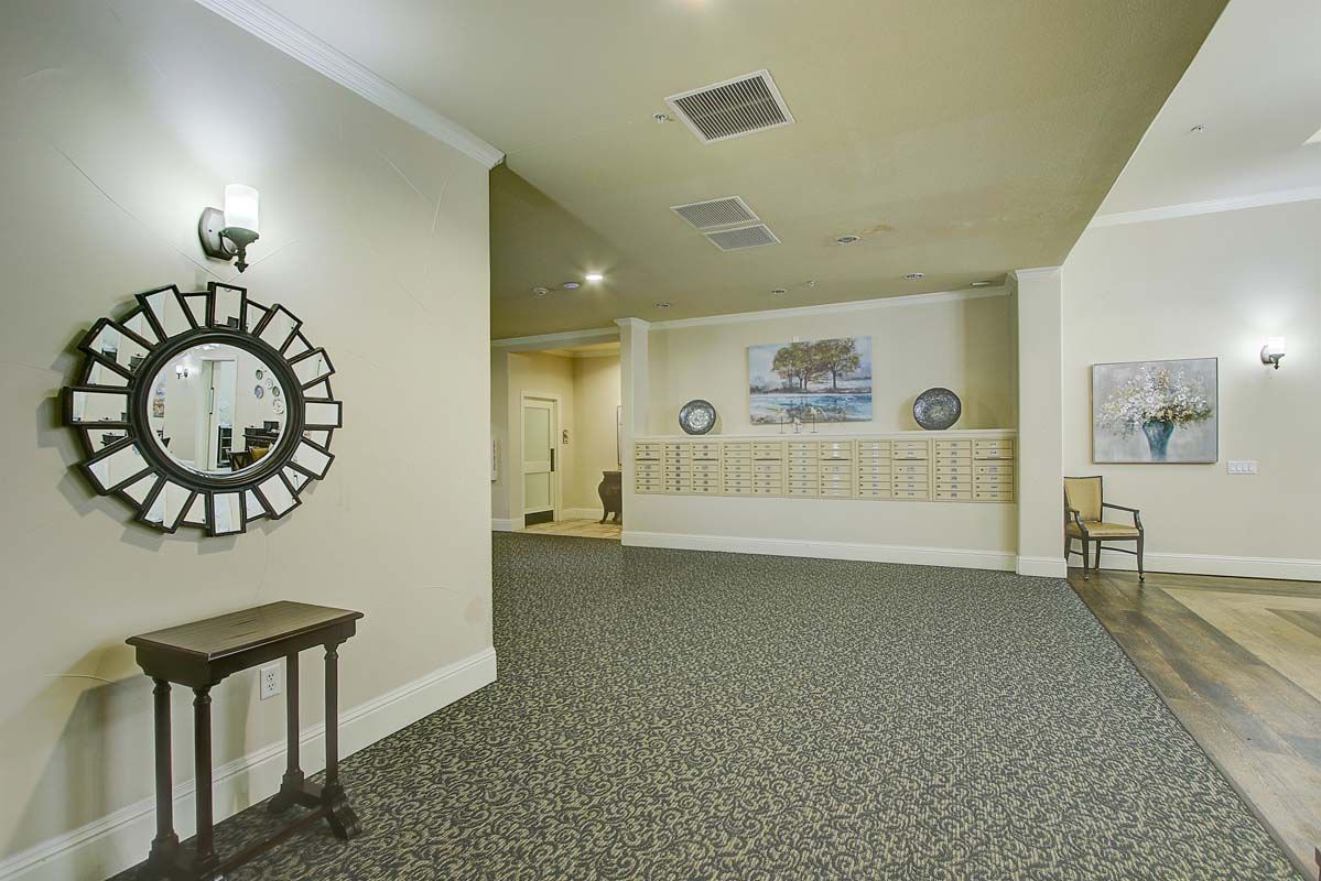 A hallway with a decorative mirror, carpeting, and mailboxes on the wall.