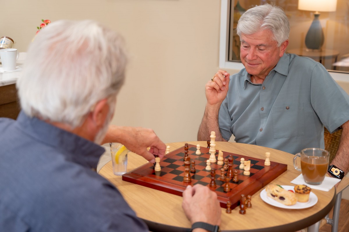 Two elderly men playing a game of chess at a table.