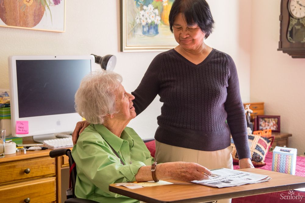 A caregiver provides support to an elderly woman at home.