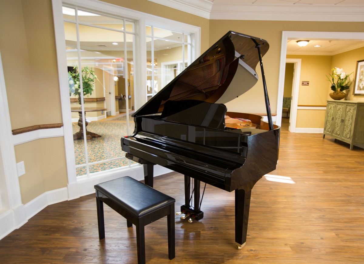 A grand piano with a bench in a well-lit music room.
