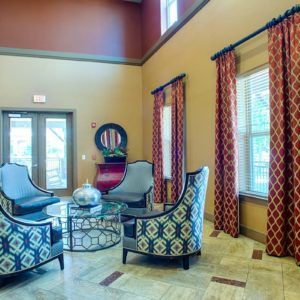Elegant living room with patterned armchairs and large windows adorned with vibrant curtains.