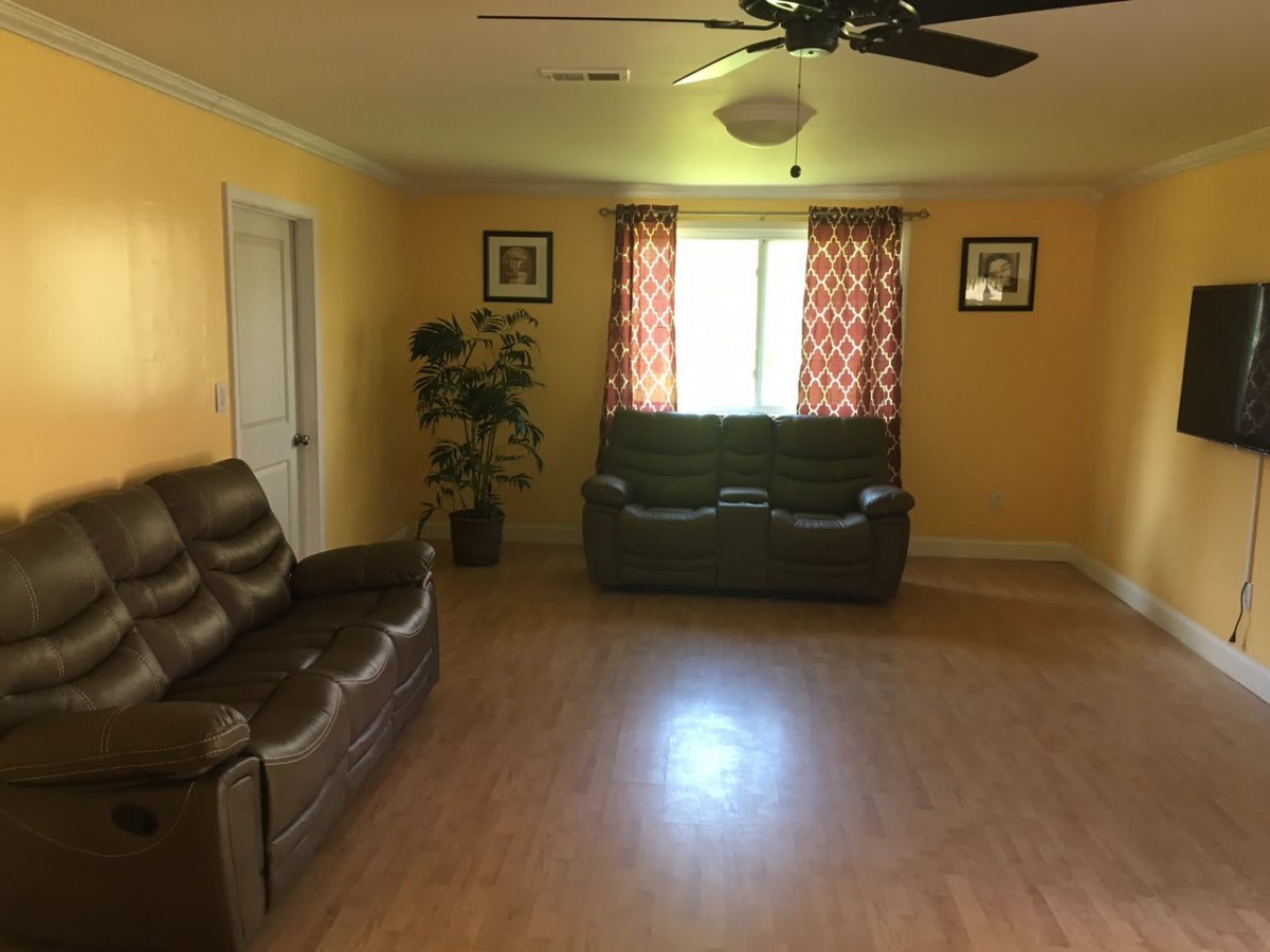 A cozy living room with yellow walls, featuring two leather sofas and a window with patterned curtains.