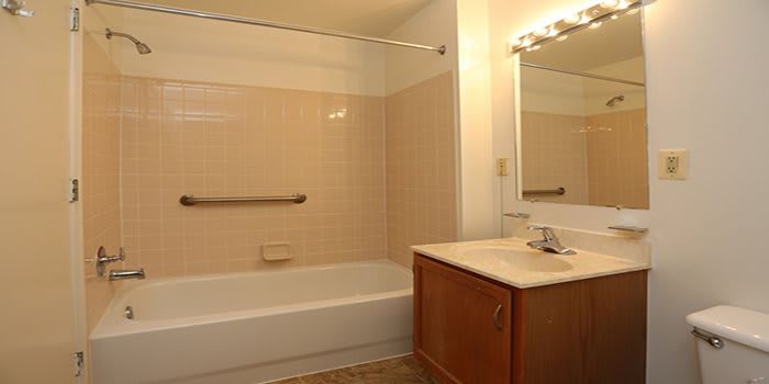 A clean bathroom with a bathtub, vanity, and large mirror.