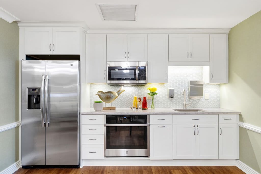 A modern kitchen with white cabinets and stainless steel appliances.