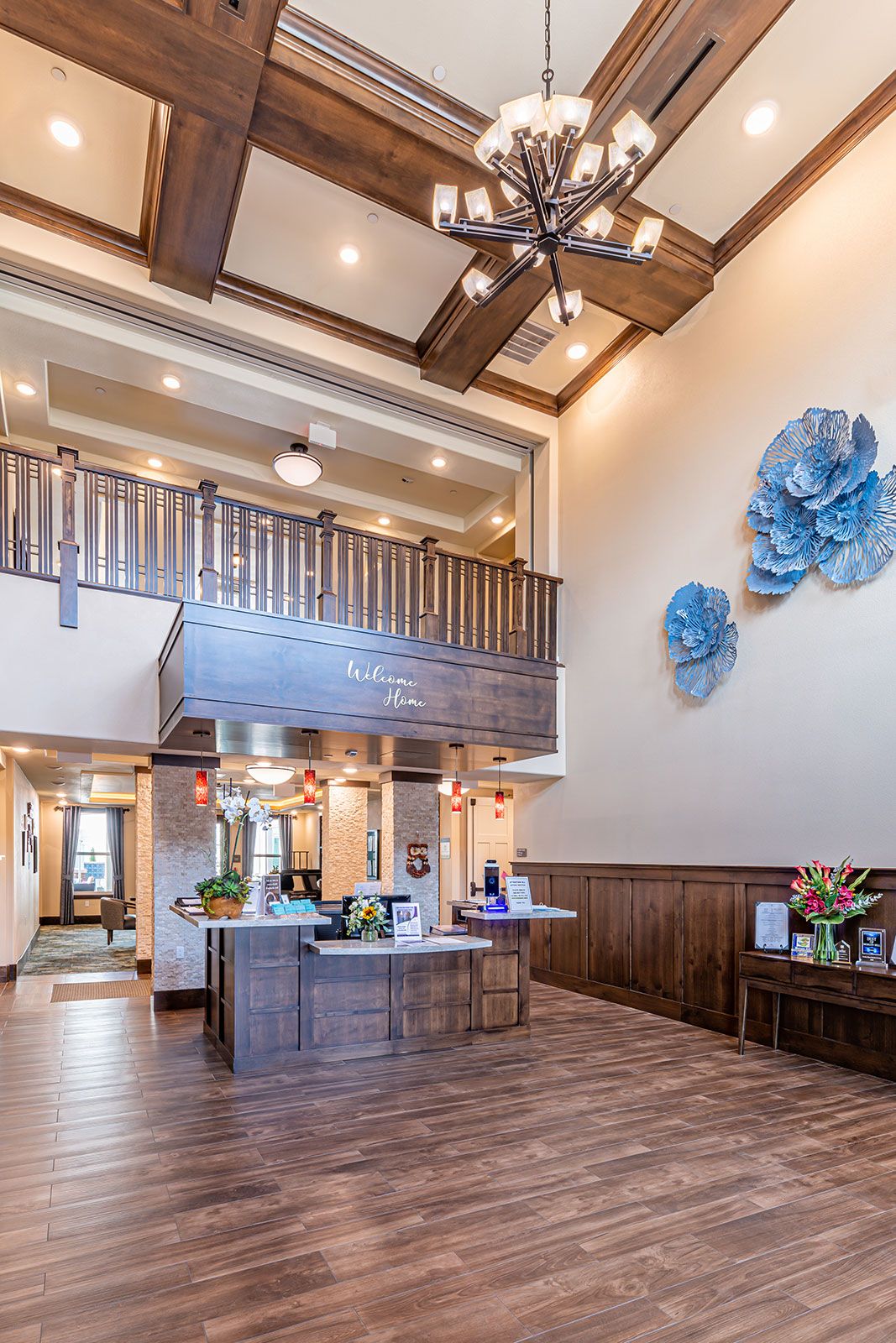 A modern lobby with wooden decor and blue wall art, featuring a reception desk and a chandelier.