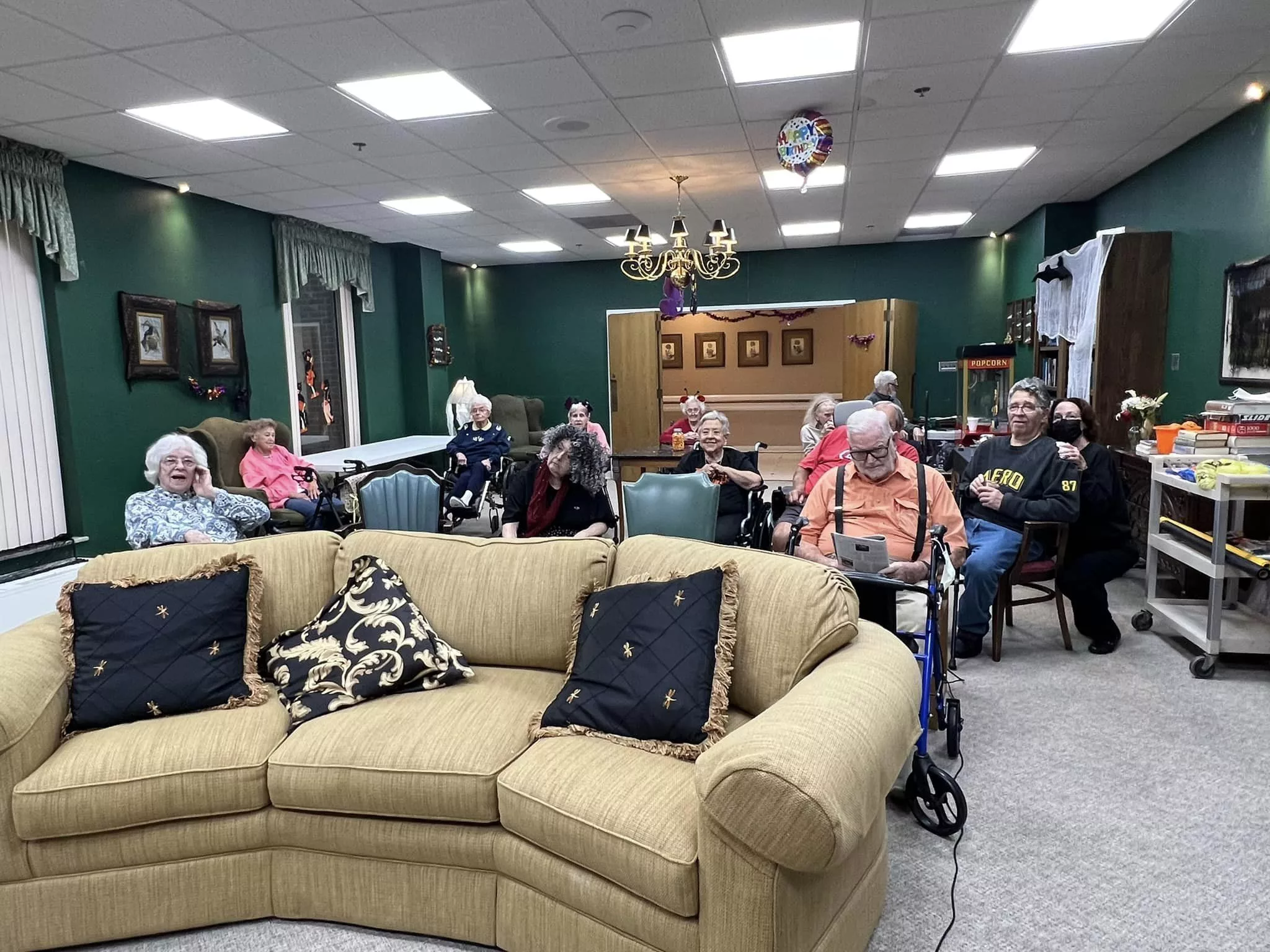 A group of elderly people gathered in a community living room setting, enjoying a social activity.