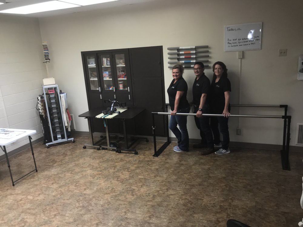 A group of people in an office setting create a fun optical illusion by appearing to levitate a broom.