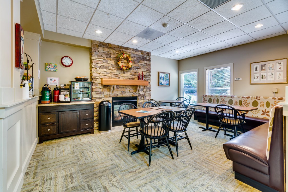 A cozy dining area with tables and chairs, featuring a stone fireplace and warm decor.