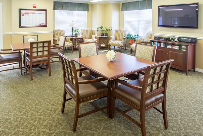 A cozy and well-furnished living room with a table, chairs, plants, and a television.