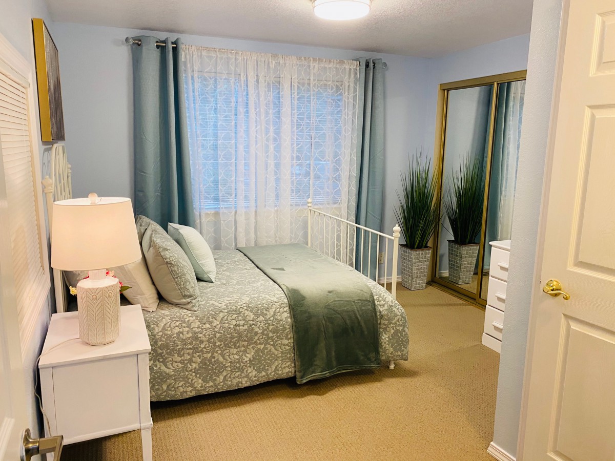 A cozy bedroom with a neatly made bed, soft lighting, and decorative plants.