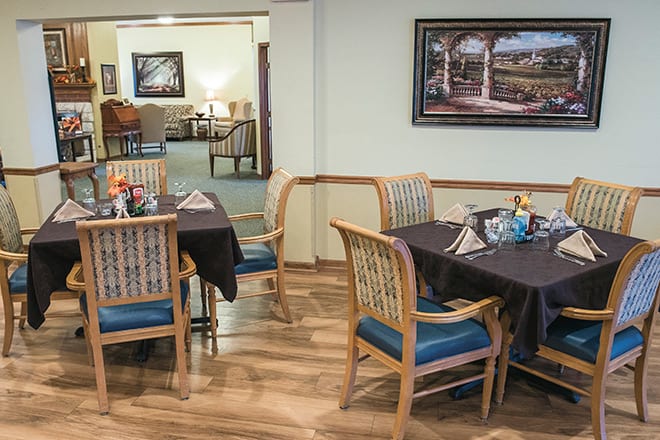 A cozy dining area with neatly arranged tables and chairs, featuring a decorative painting on the wall.