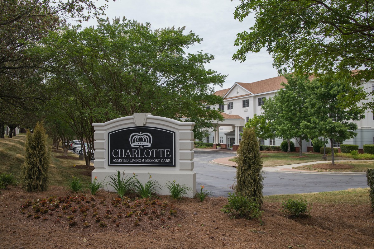 Entrance sign to a residential area with surrounding trees and landscaping.