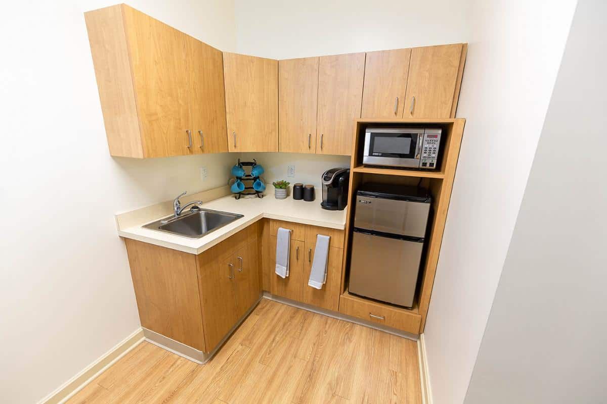 A compact kitchen with wooden cabinets, a sink, a microwave, and various appliances.