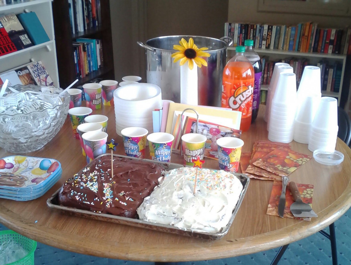 A table set up for a celebration with cakes, snacks, and drinks.