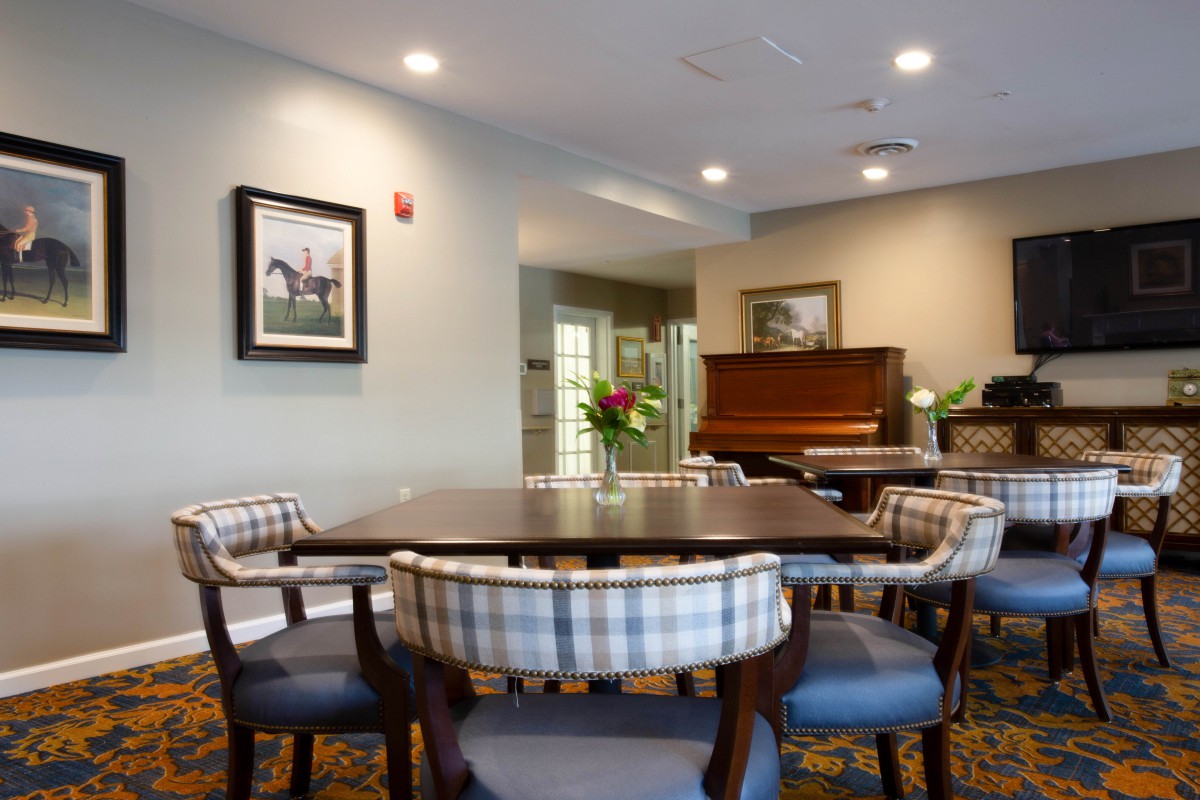 A cozy dining area with a table, chairs, and a piano in the background.