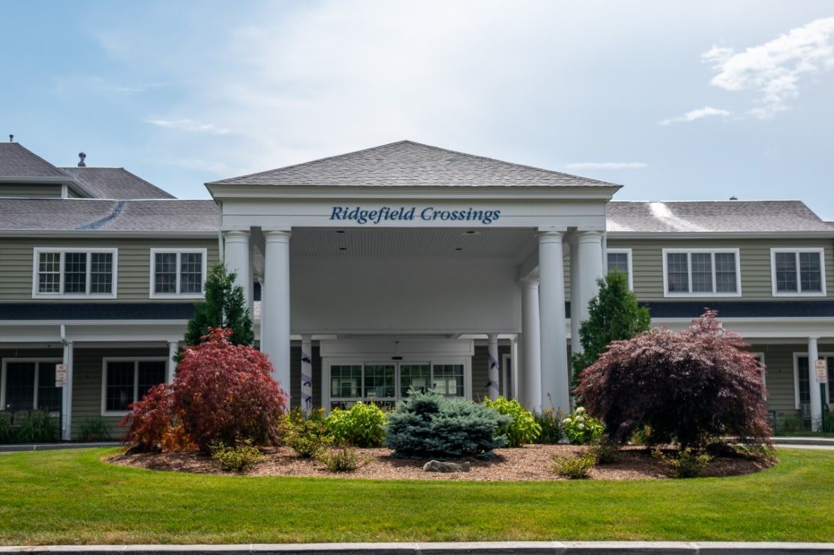 A well-maintained building entrance with columns and landscaped surroundings.