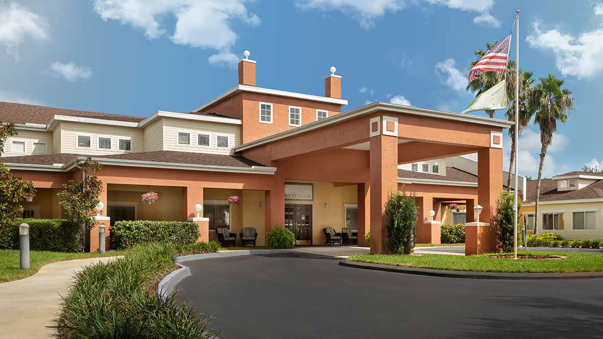 A welcoming hotel entrance with a covered driveway and landscaped surroundings.