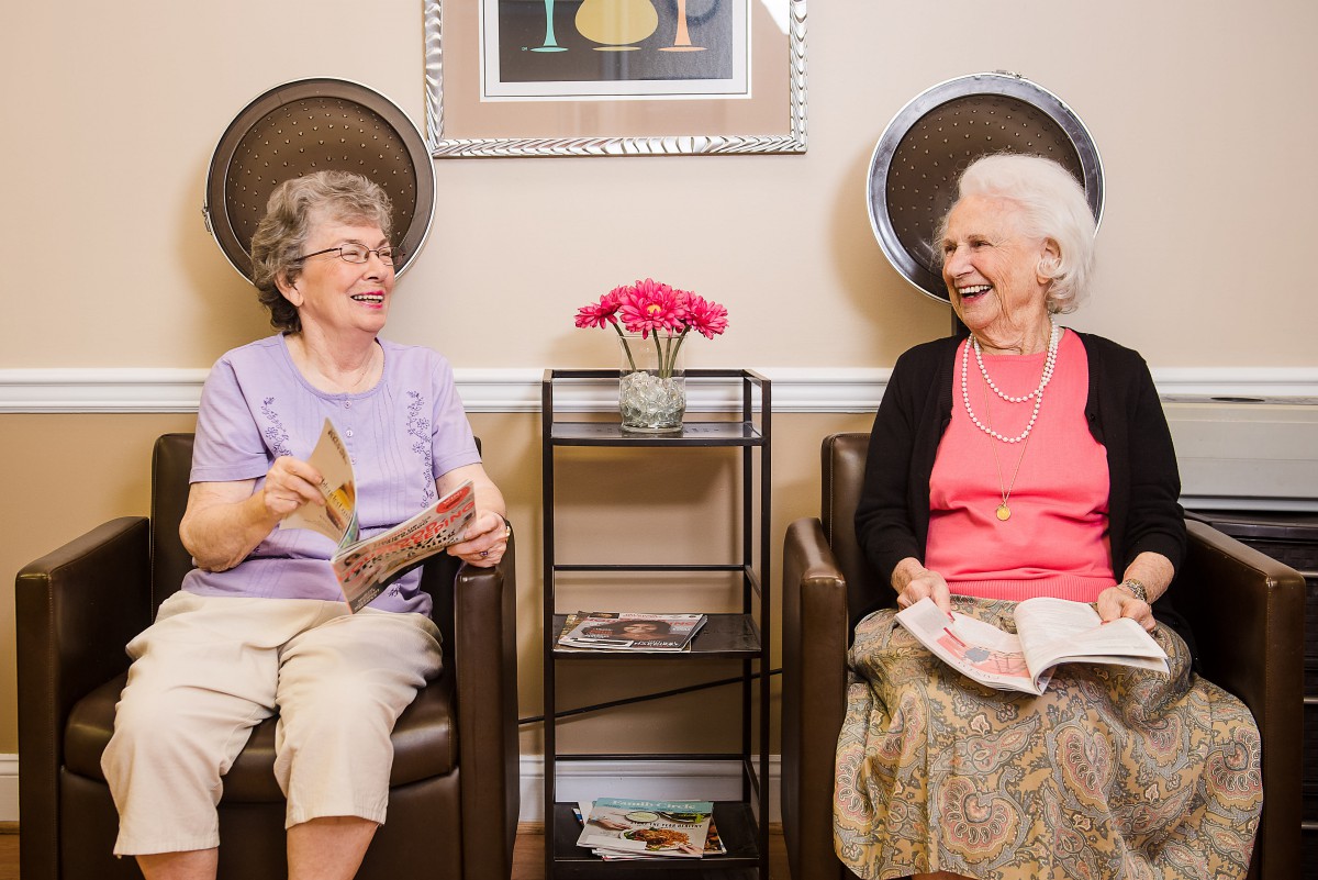 Two elderly women enjoying a relaxing day at the salon, engaging in conversation and reading.