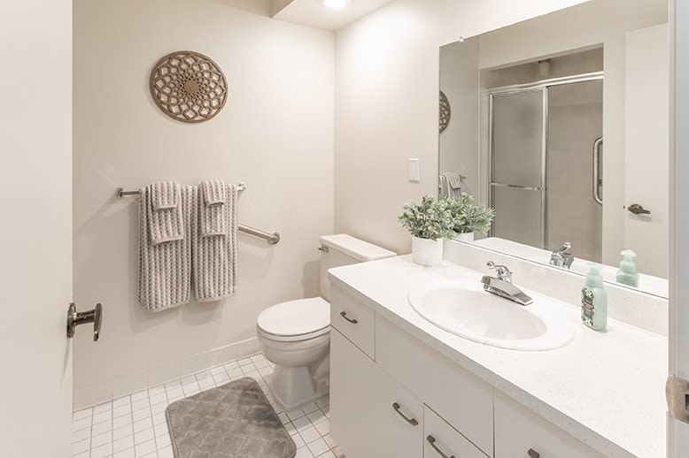 A clean and well-organized bathroom with a modern design, featuring a sink, mirror, toilet, and shower.