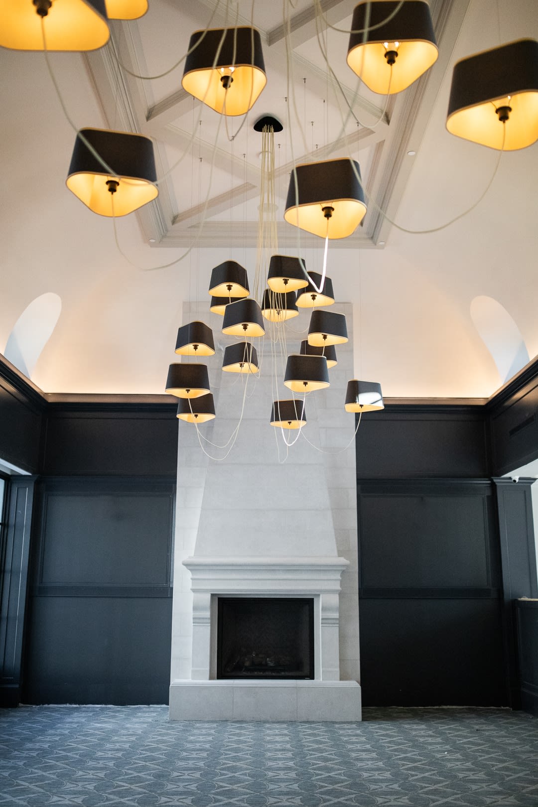 A luxurious interior featuring a modern chandelier and a tall white fireplace.
