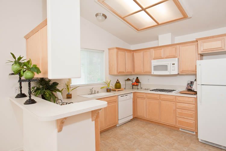 A modern kitchen with wooden cabinets and bright lighting.