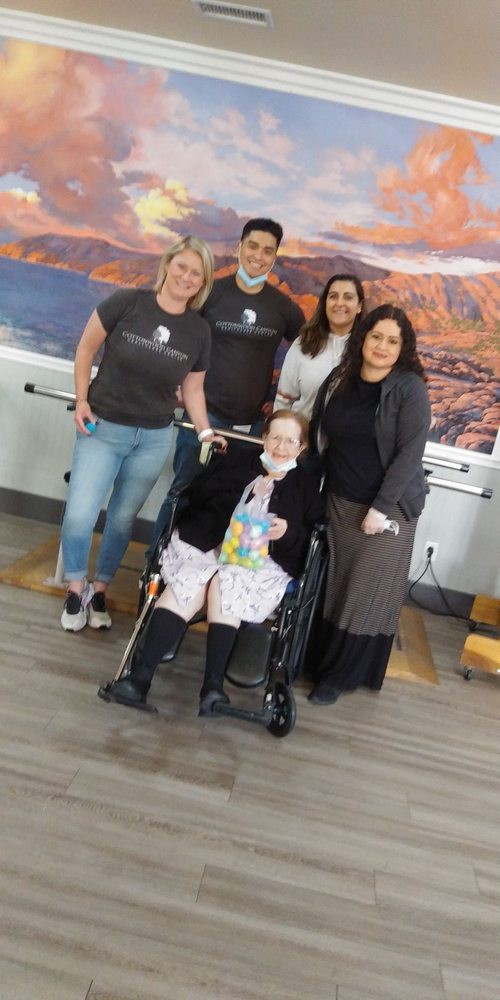 A group of people posing with an elderly woman in a wheelchair indoors.