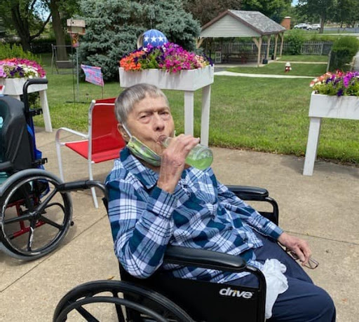 A senior enjoying a snack in a wheelchair surrounded by blooming flowers.