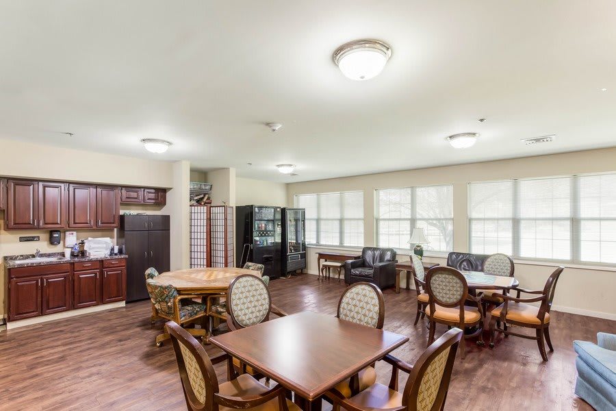 A spacious dining area with multiple tables and chairs, featuring large windows and ample lighting.