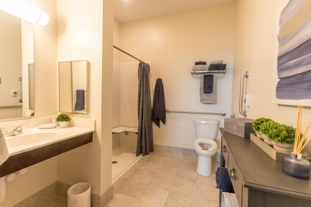 A modern bathroom with a shower, toilet, and sink in neutral tones.