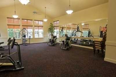 A well-lit gym with various exercise equipment and large mirrors.
