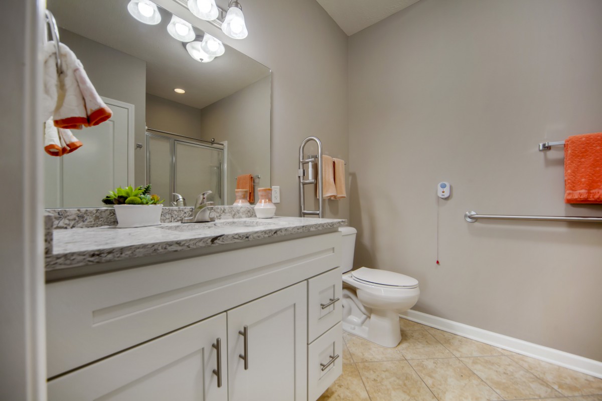 A modern bathroom featuring a sink, mirror, toilet, and stylish lighting.