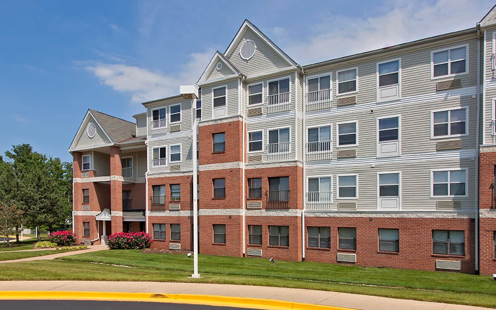 A modern residential apartment building with red brick and gray siding.