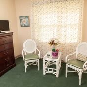 A cozy living room corner with two wicker chairs, a small table, and a window with curtains.