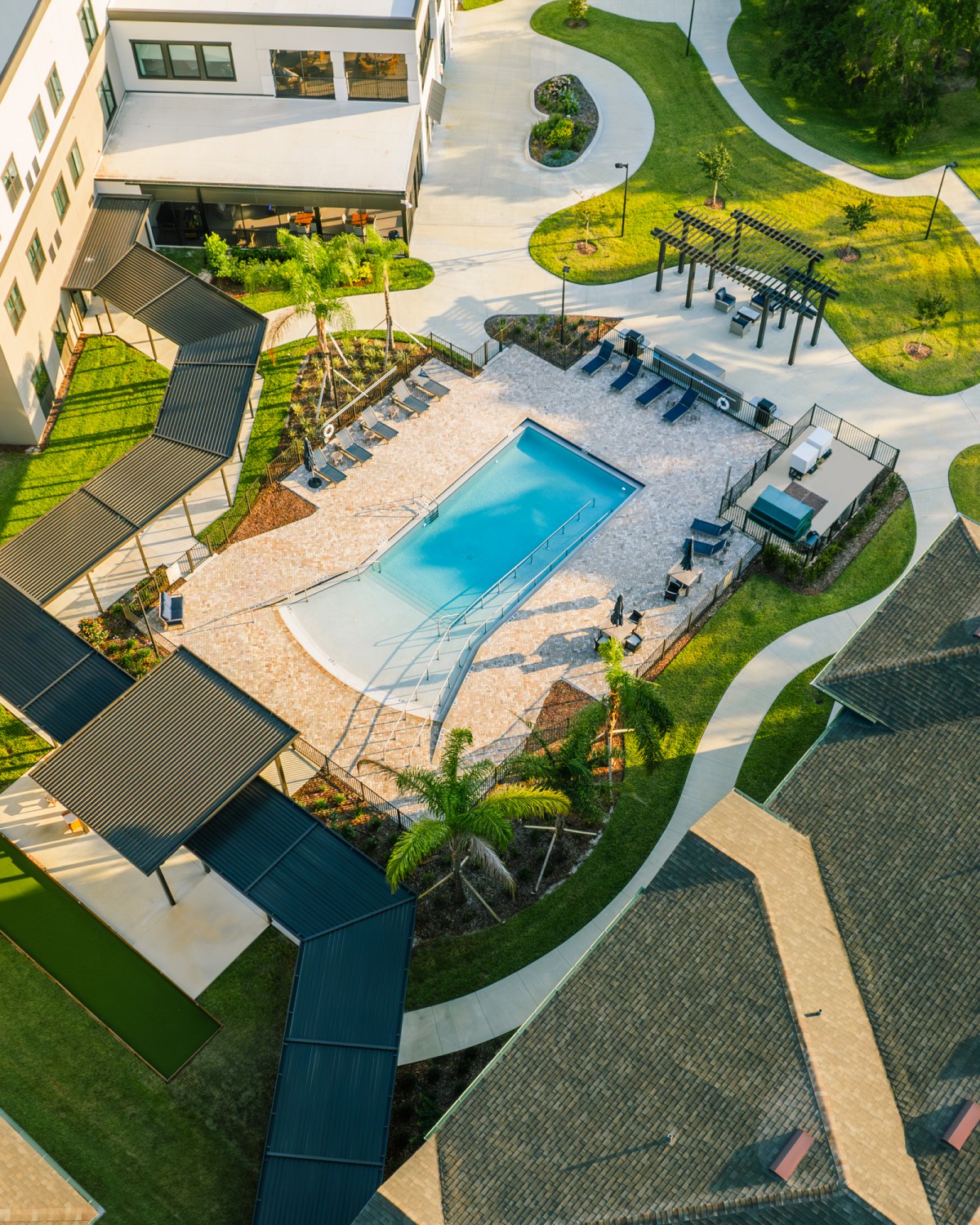 Aerial view of a residential outdoor area featuring a swimming pool surrounded by landscaped pathways and leisure spaces.