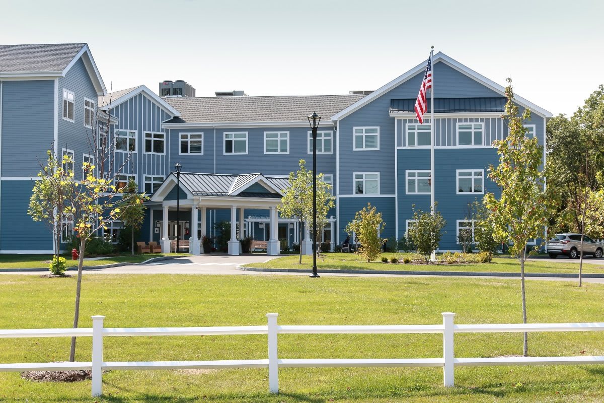 A multi-story residential building with a well-kept lawn and an American flag.