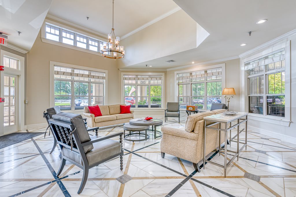 A modern and luxurious living room with large windows, elegant furniture, and a chandelier.