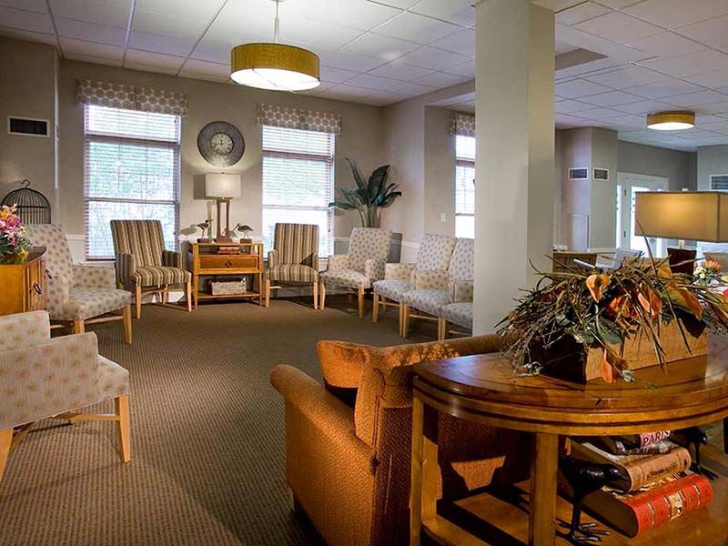 A cozy waiting room with comfortable seating, a round table, and soft lighting.