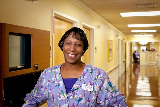 A cheerful nurse welcomes you in a hospital corridor.