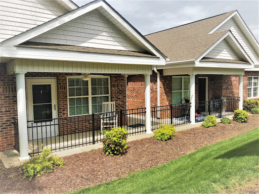 A view of a well-maintained residential building featuring porches and landscaped gardens.