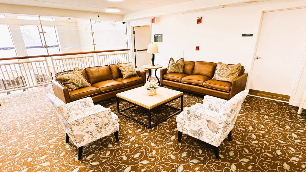 A cozy living room setup featuring leather sofas, patterned chairs, and a central coffee table.