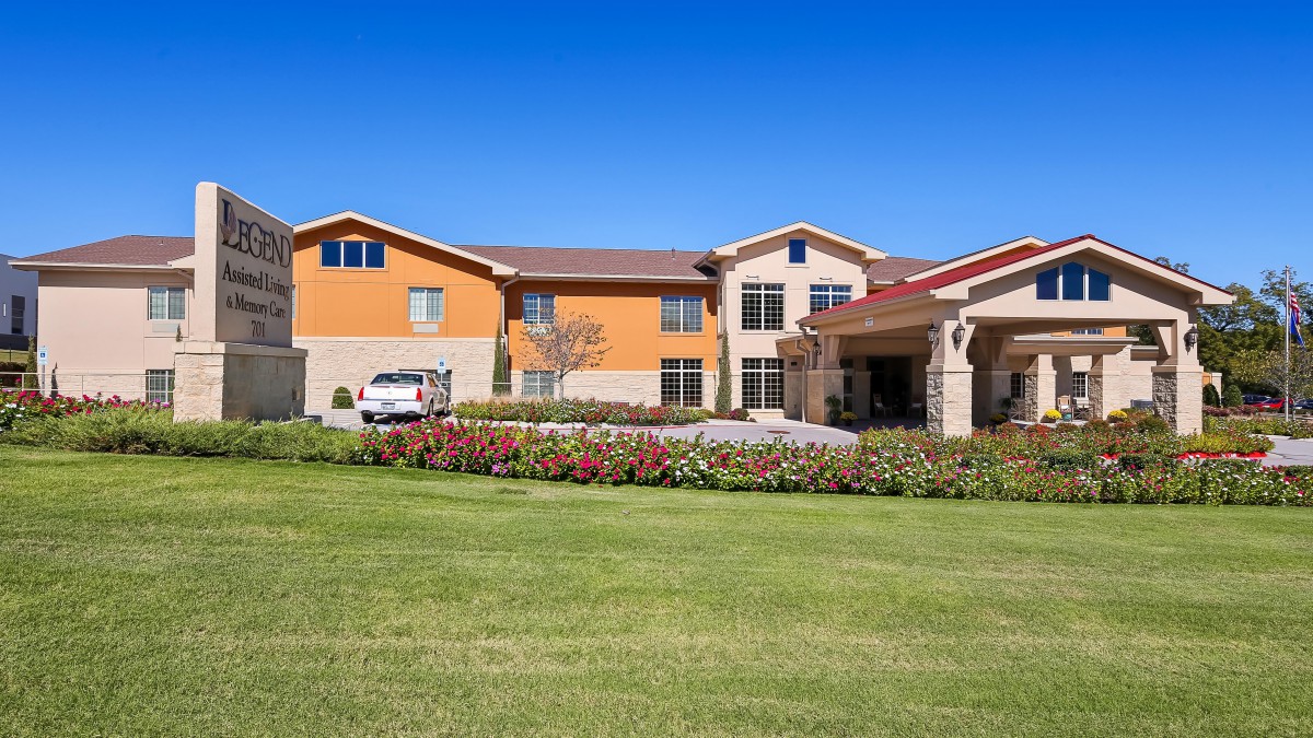 A modern residential building surrounded by a well-maintained lawn under a clear blue sky.